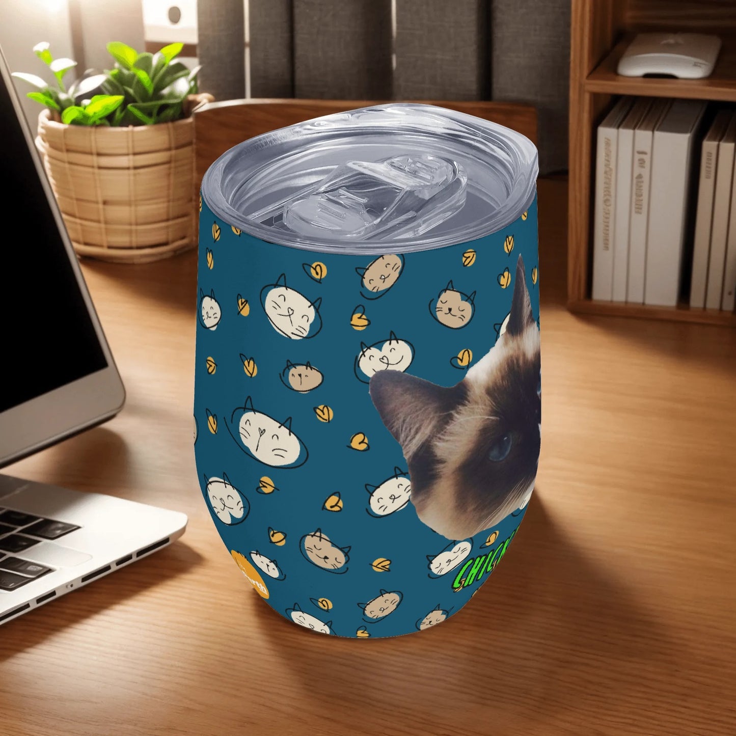 Tumbler with cat pattern on a desk next to a laptop